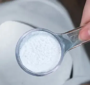 Fine white powder heaped in a small measuring scoop on a plain light background
